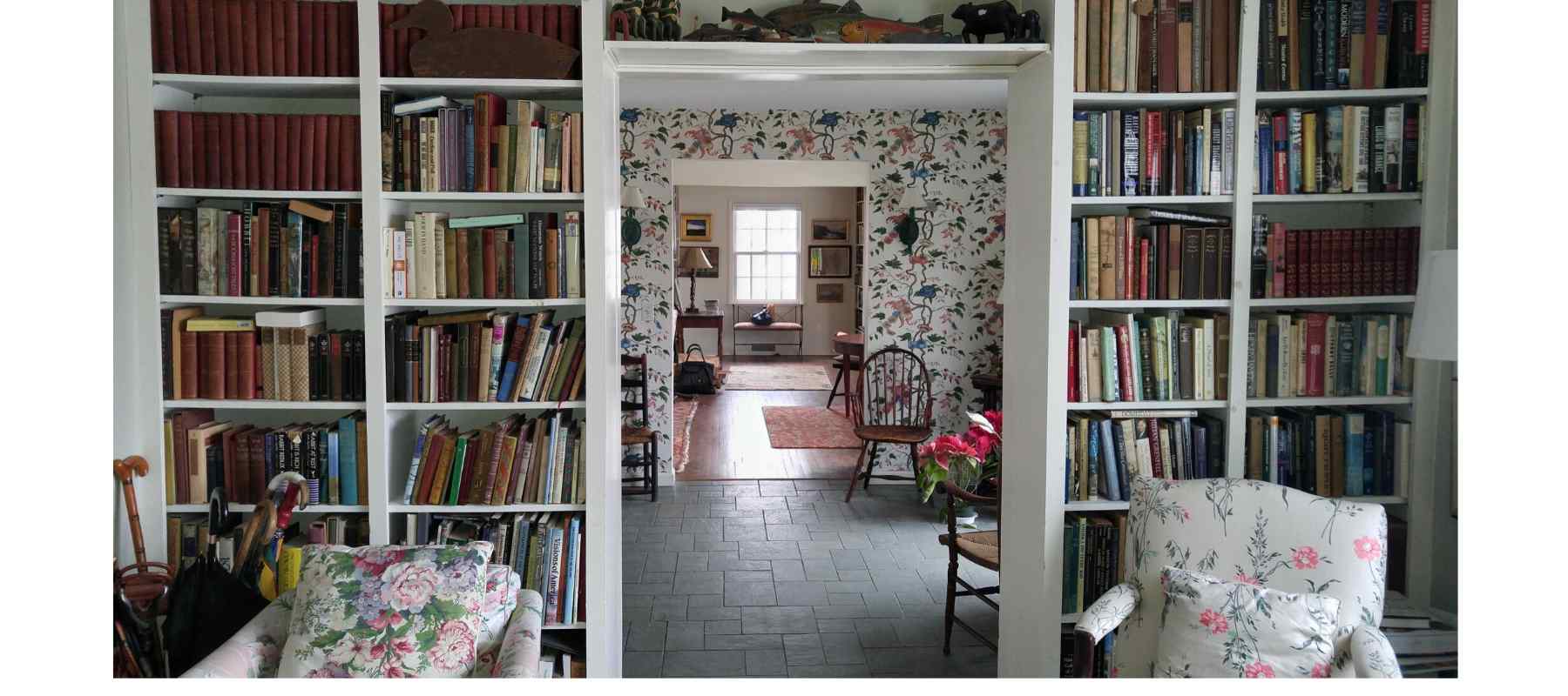 large white bookcase over doorway with floral armchairs