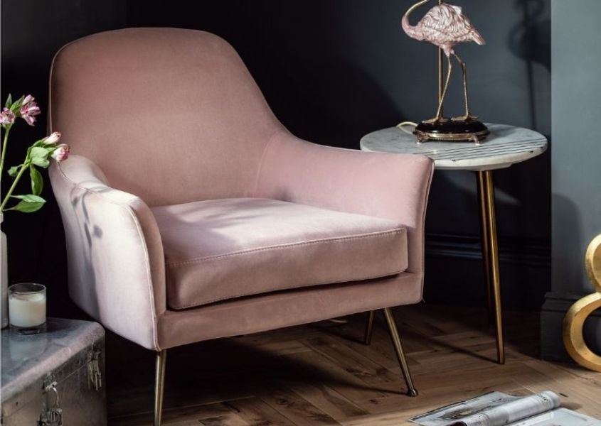 Pink velvet armchair in room with dark walls and flamingo side lamp