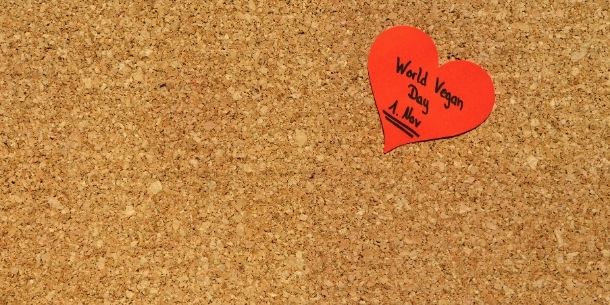 Red heart shaped sticker World Vegan Day words stuck on cork board