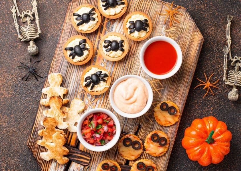Platter of Halloween themed foods, including spider cupcakes and pumpkin biscuits