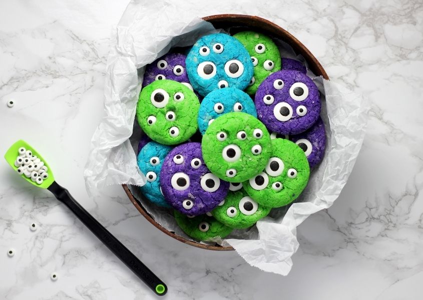 Bowl of green, purple and blue Halloween biscuits with wide eye decorations
