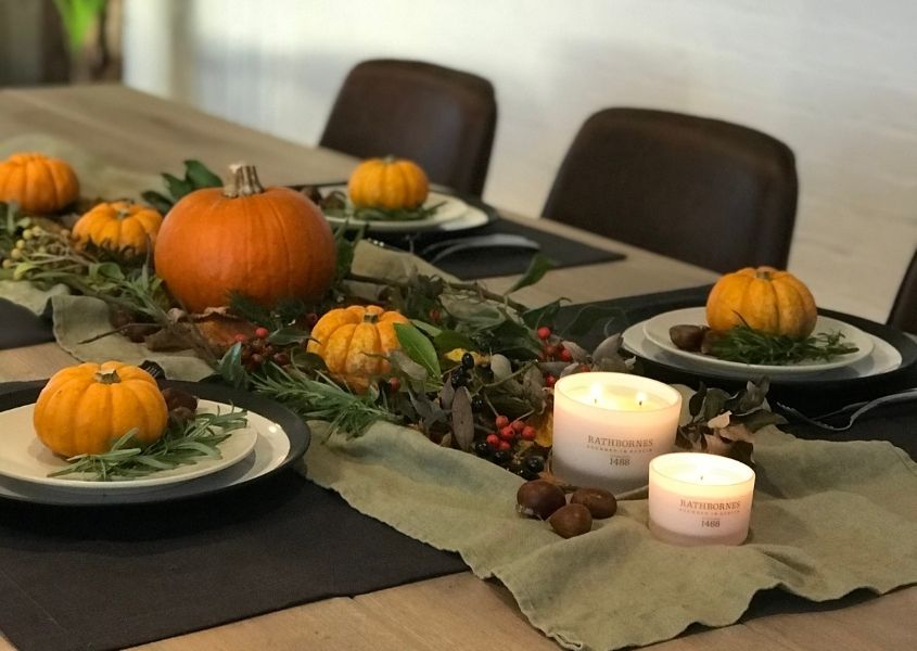 Wooden table decorated in Halloween theme with small pumpkins on plates and in middle of the table