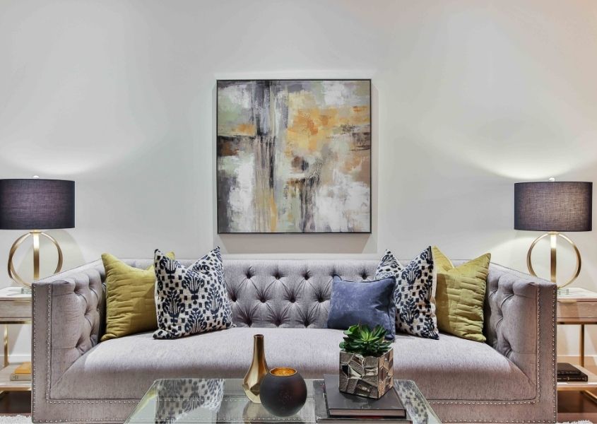 Grey fabric chesterfield sofa with large artwork on the wall and two table lamps