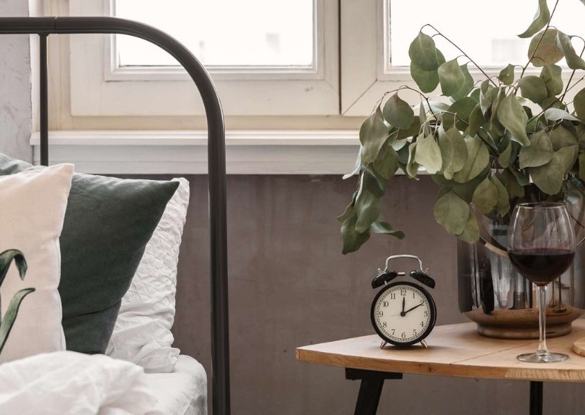 Metal bedframe with wooden bedside table and round clock