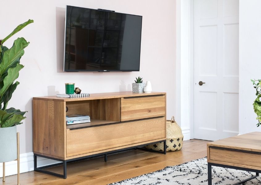 industrial tv unit with tv on wall above and white rug on floor