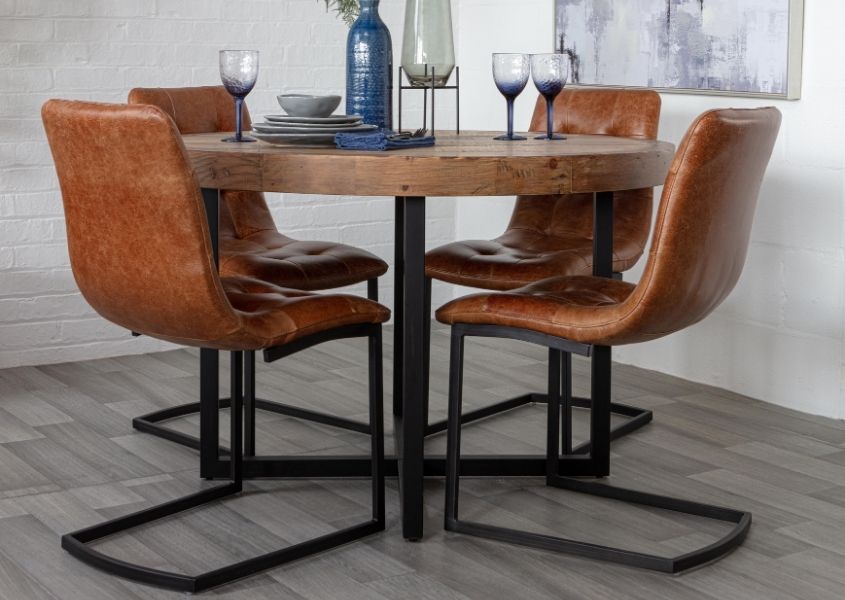 Brown leather dining chairs around a round reclaimed wood dining table
