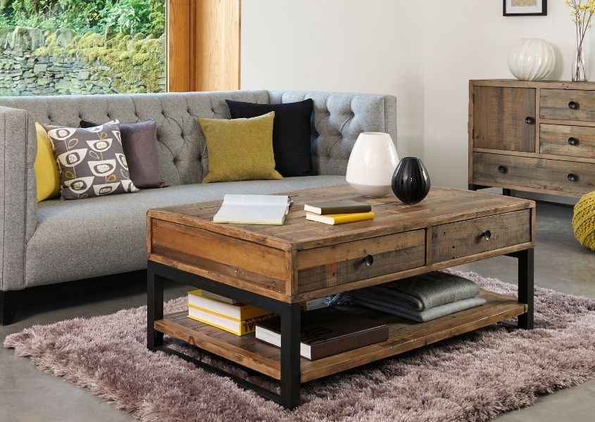 Industrial reclaimed wood coffee table with two drawers in front of a grey sofa