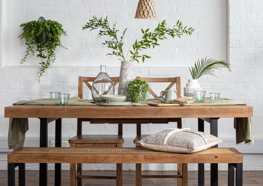 Industrial dining table with green plants for how to host the perfect dinner party blog