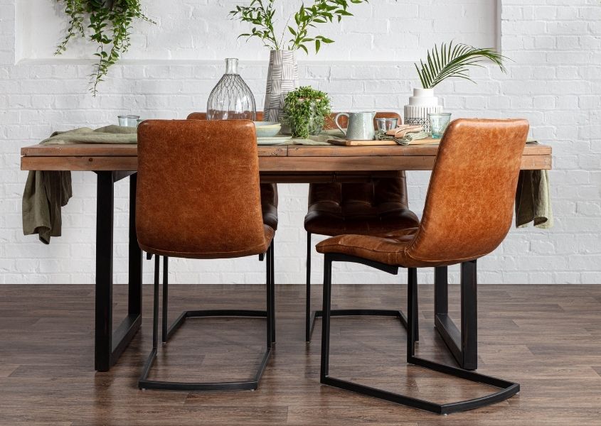 Industrial reclaimed wood dining table with four tan leather industrial dining chairs