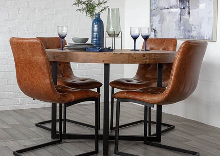 Round industrial dining table with four brown leather dining chairs