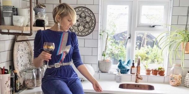 woman sat on kitchen work surface holding glass of wine