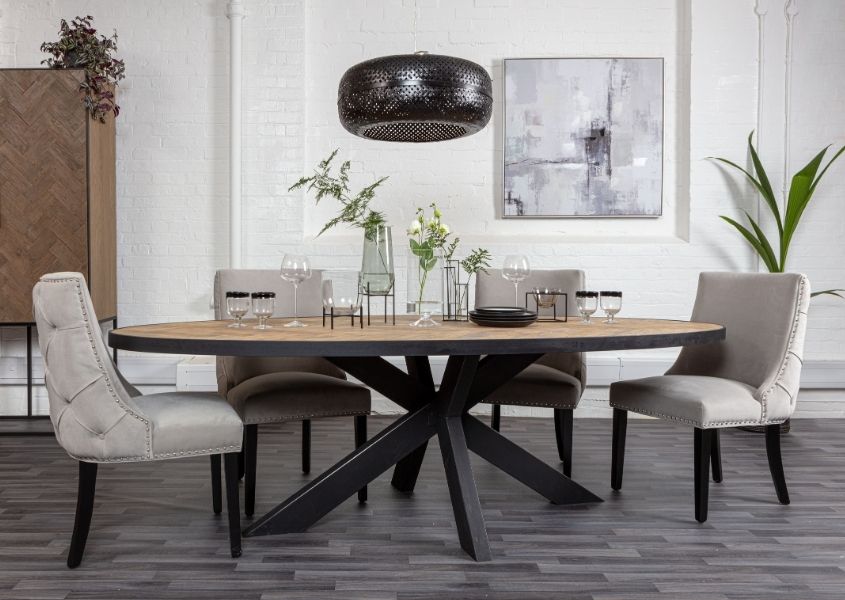 Oval industrial oak dining table with black spider leg and grey velvet dining chairs