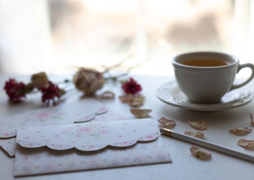 floral note pad and cup of tea on a white writing desk