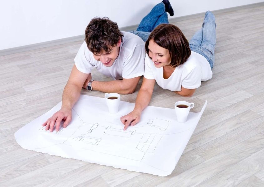 man and woman lying on the floor reading plans for tips for planning the living room and bedroom in your new home blog