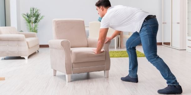Man moving armchair for tips to plan a new layout for your living room and bedroom blog
