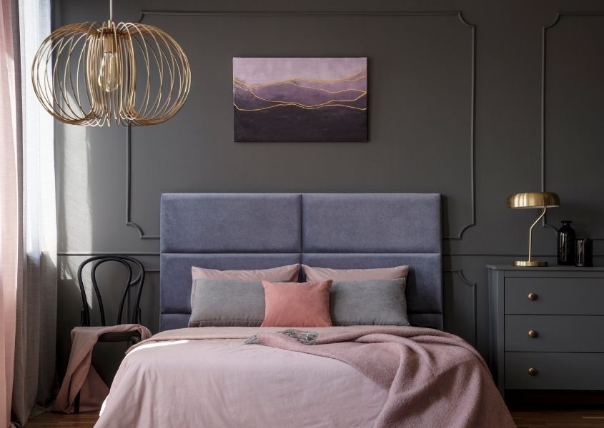 pastel coloured bedroom with brass hanging pendant light and bedside light