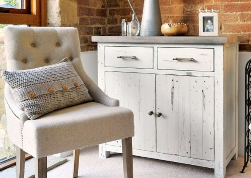 Cream fabric armchair in front of white wooden sideboard