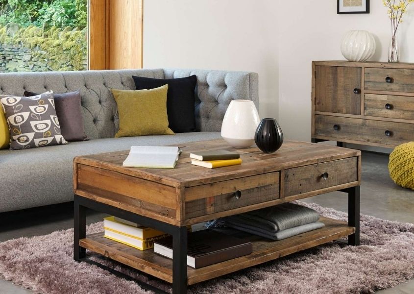 Industrial coffee table on rug with grey sofa and reclaimed wood sideboard in background