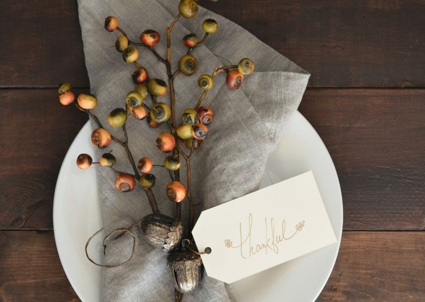bunch of autumn berries tied with string thankful label attached on a rustic dining table