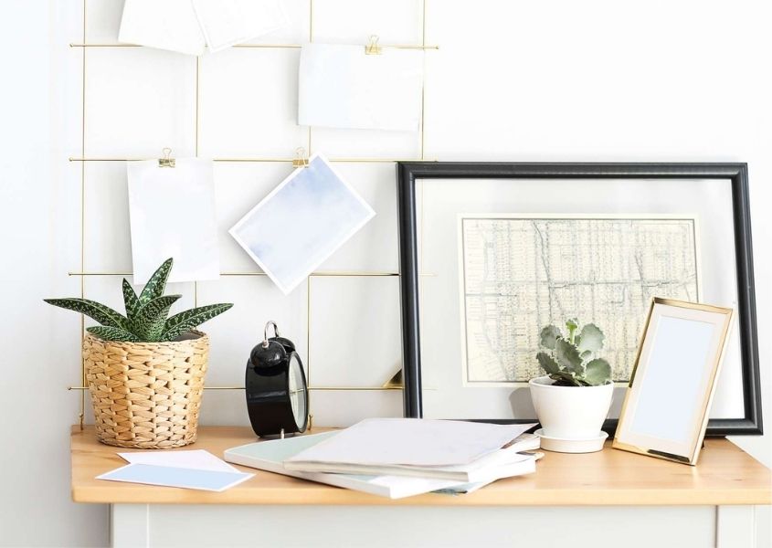 White home office desk with black framed print and small plant pots