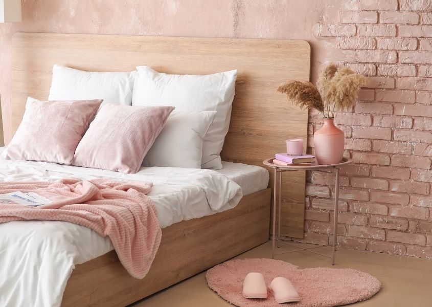 pink bedroom with solid wood bed and exposed brick wall