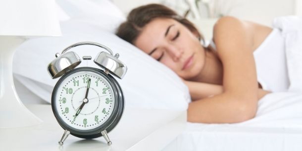 woman sleeping in bed with alarm clock