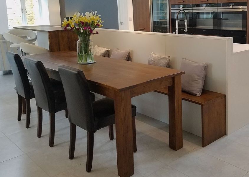 Wooden table and dining bench against kitchen island with grey chairs