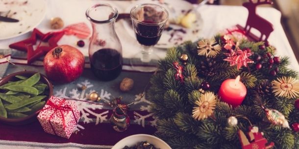 Close up of Christmas dining table with small pine wreath and decanter and glass of red wine