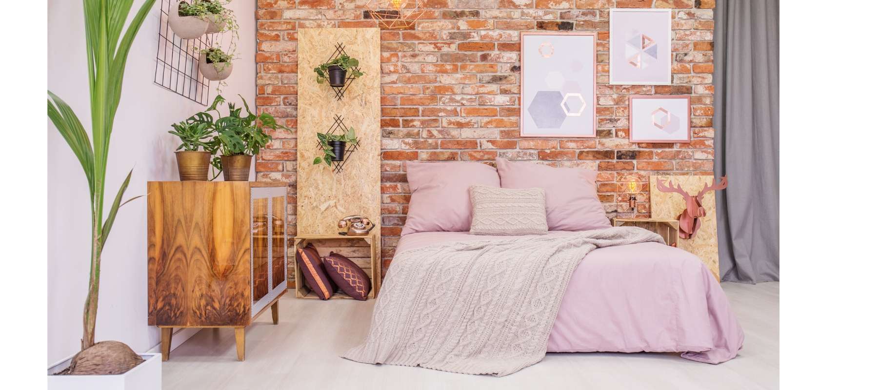Double bed with blush pink covers against an exposed brick wall